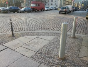 Poller vor dem Wirtshaus "Henne". Nachdem rechts die historischen Poller mehrfach umgefahren wurden, setzte das Bezirksamt diese massiven Poller ein. Der linke wurde bereits wieder erkennbar angefahren.